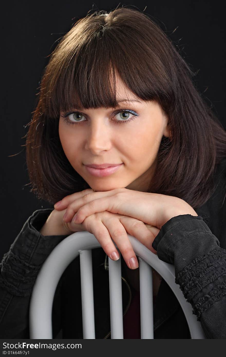 Young beautiful woman sit on chair on black background