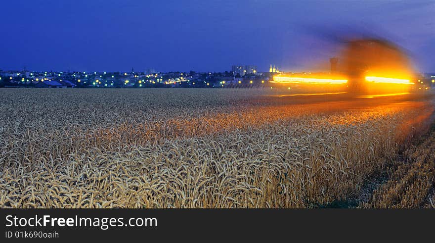 Harvester at work in the dark, near a city