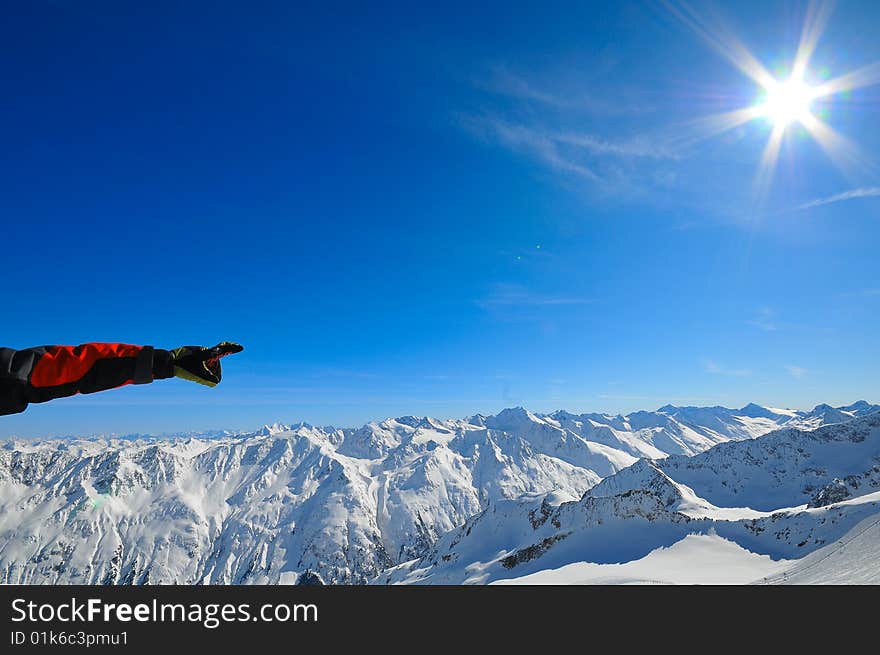 Man's hand pointing out in mountains.