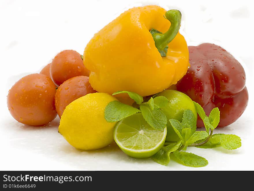 Whole and a lemon half,  pepper and tomatoes on a white background. Whole and a lemon half,  pepper and tomatoes on a white background