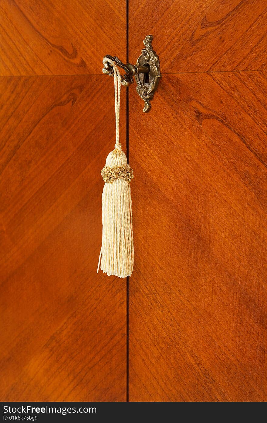 Bronze key with a tassel in a keyhole