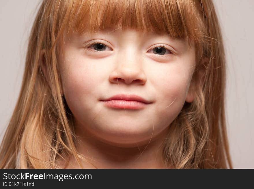 Portrait of an Adorable Red Haired Girl on a Grey Background.