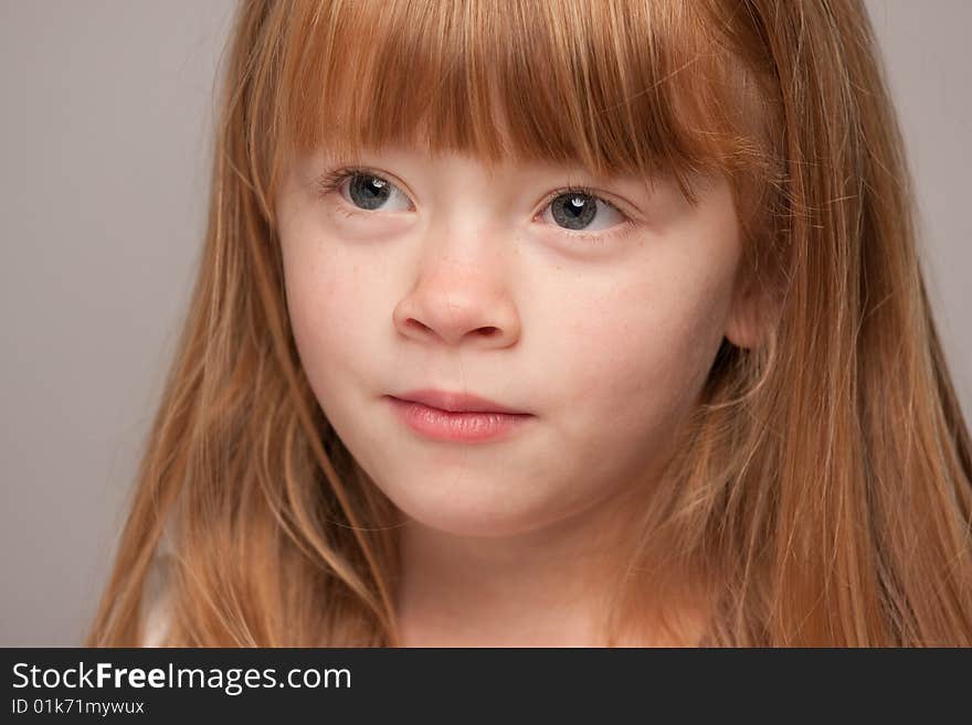 Portrait of an Adorable Red Haired Girl on a Grey Background.