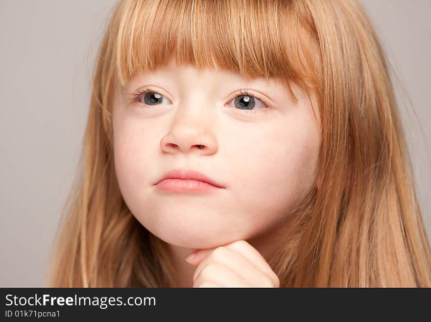 Portrait of an Adorable Red Haired Girl on a Grey Background.