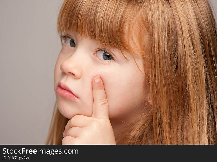 Portrait of an Adorable Red Haired Girl on a Grey Background.