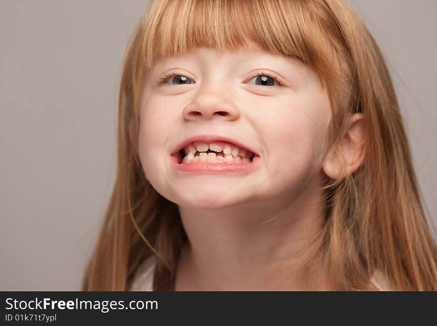 Portrait of an Adorable Red Haired Girl on a Grey Background.