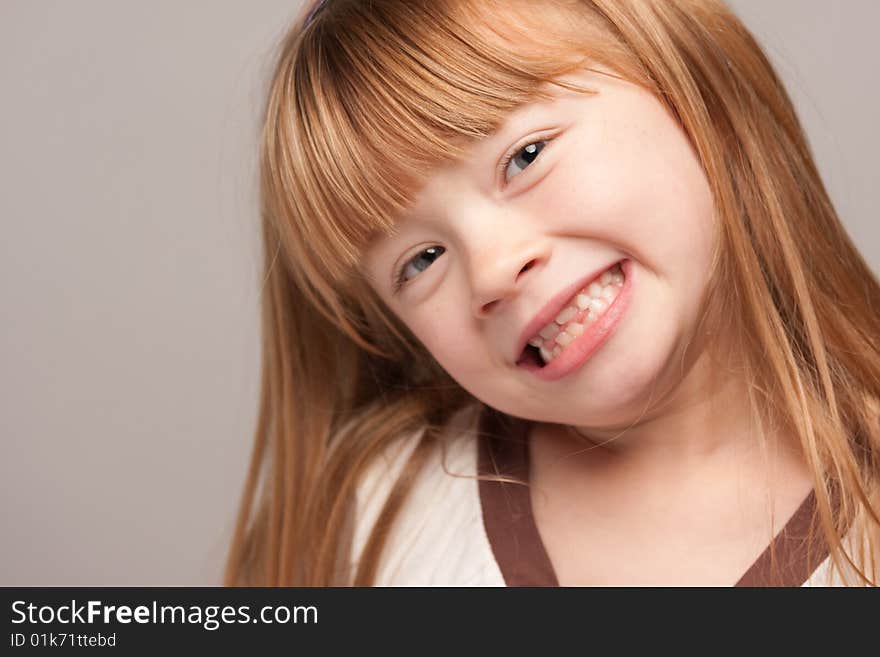 Portrait of an Adorable Red Haired Girl on a Grey Background.