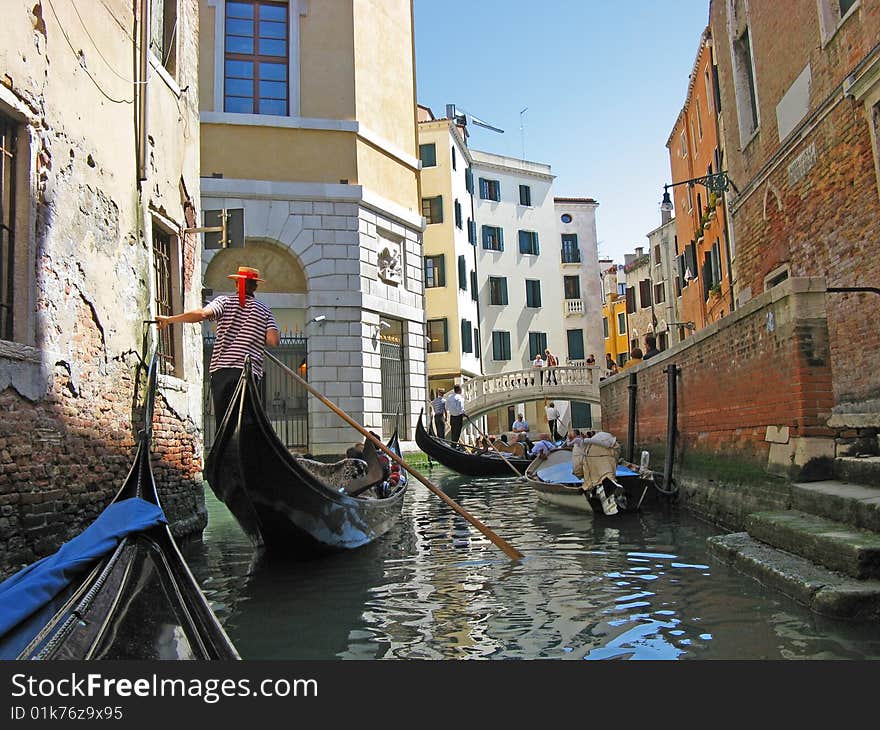 The gondoliers floats on the channel of Venice with tourists. The gondoliers floats on the channel of Venice with tourists