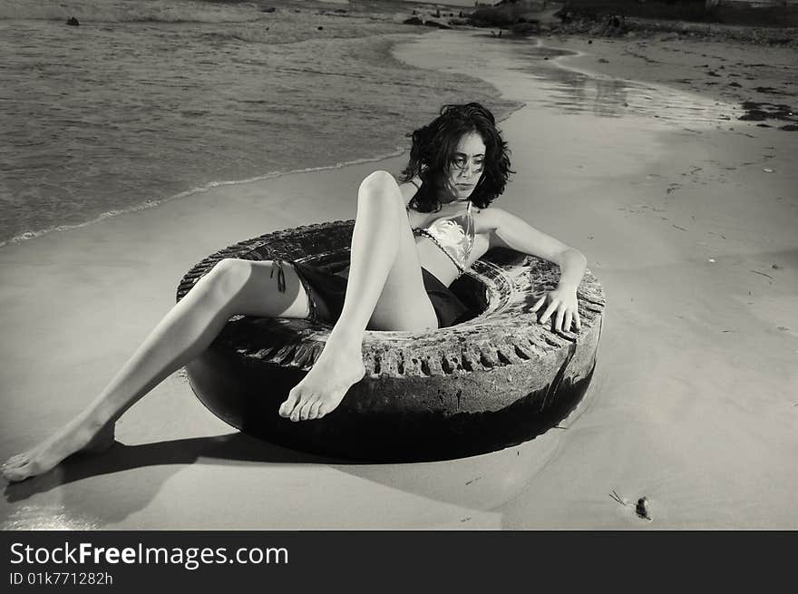 Portrait of young fashion female on the sand over tire. Portrait of young fashion female on the sand over tire