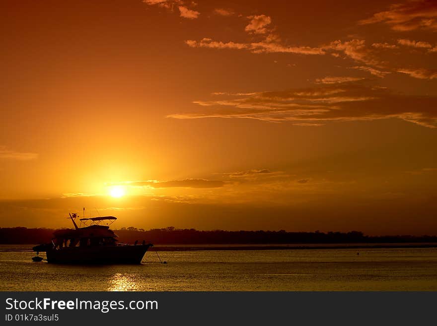 A bright orange sunset over water, with a cruiser positioned lower left. Great as a background or tourism image. A bright orange sunset over water, with a cruiser positioned lower left. Great as a background or tourism image.