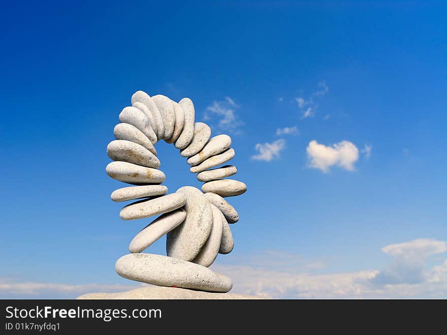 Connected ring of pebbles on a background of clouds. Connected ring of pebbles on a background of clouds