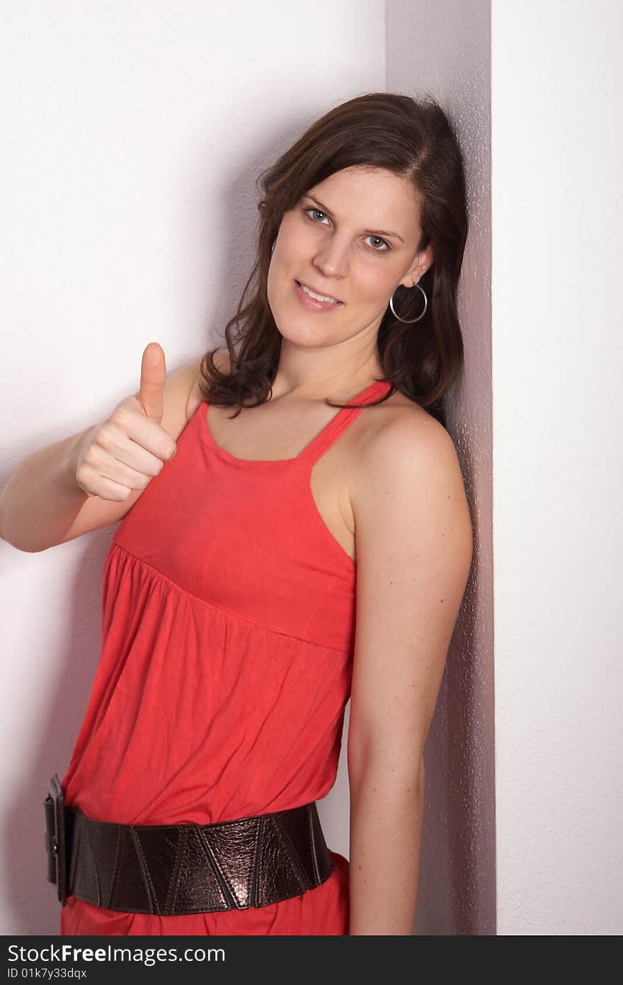 A young and woman is leaning againgst a wall. She gives a thumb up sign!. A young and woman is leaning againgst a wall. She gives a thumb up sign!