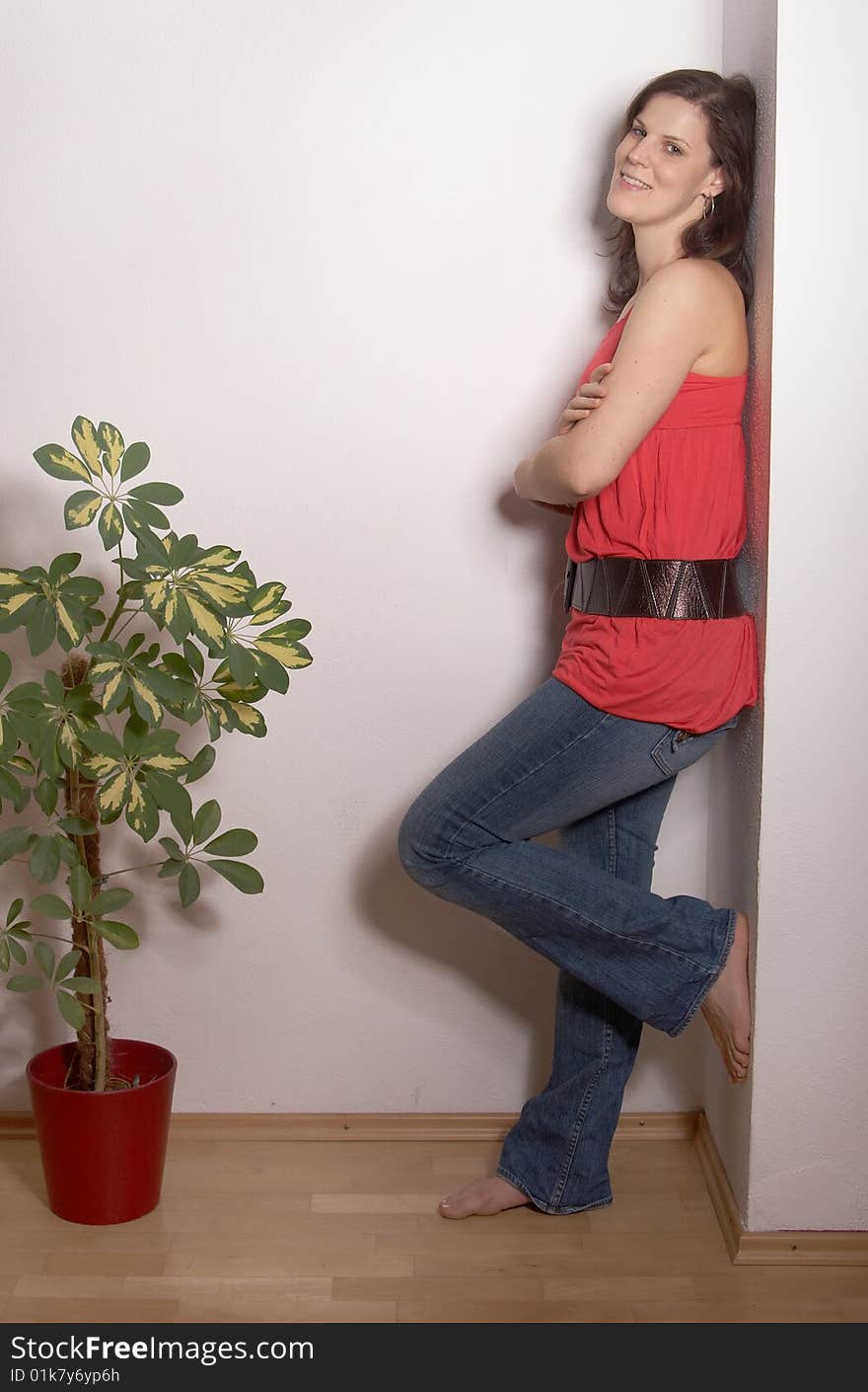 A young and sexy woman is leaning againgst a wall. She is in her new apartment with a new plant. A young and sexy woman is leaning againgst a wall. She is in her new apartment with a new plant.