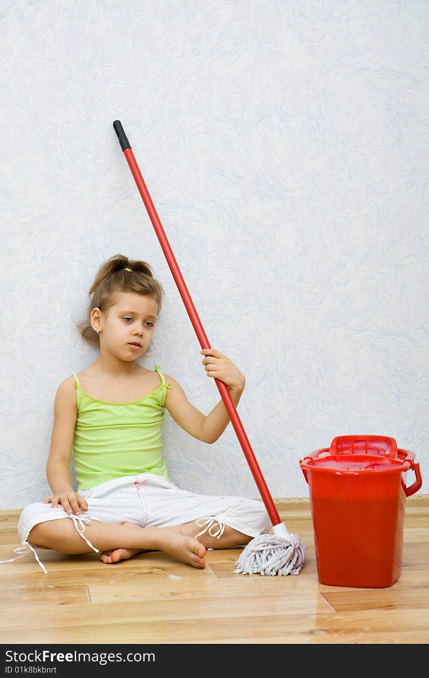 Little girl cleaning the floor in the room