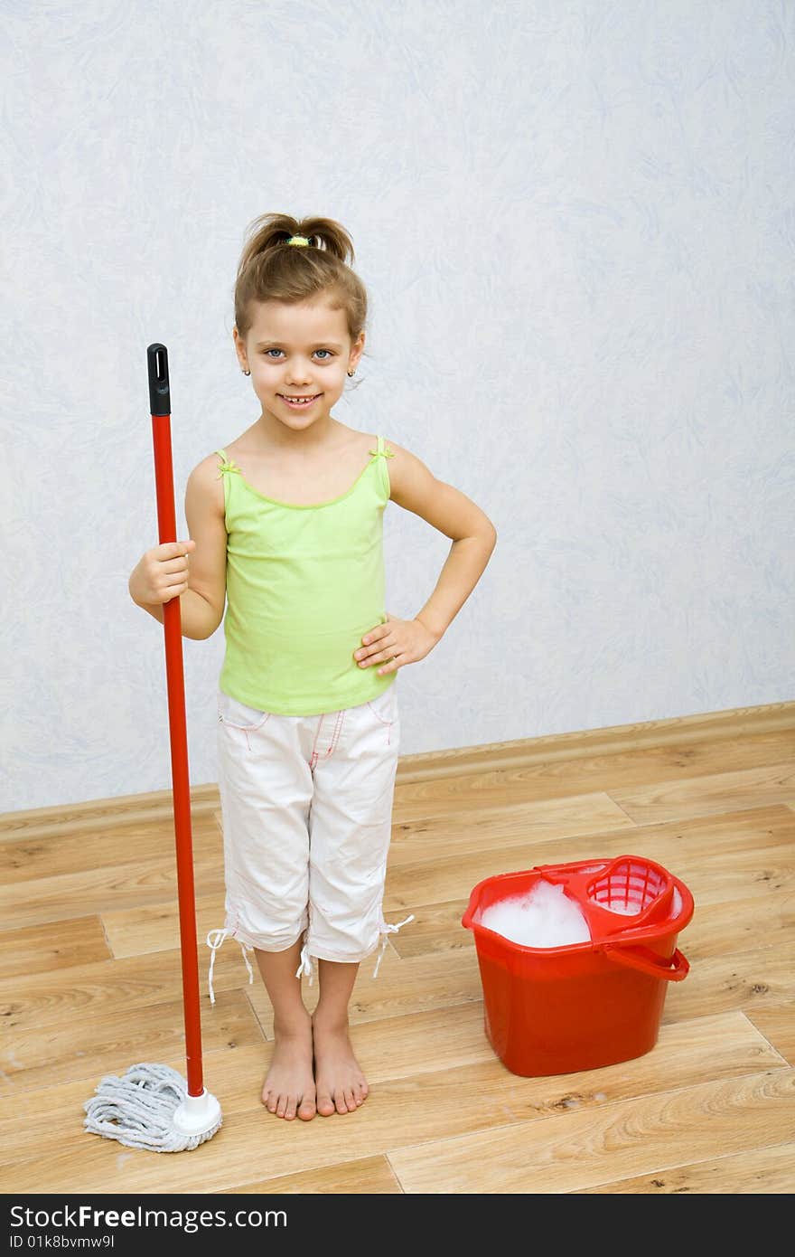 Little girl cleaning the floor in the room