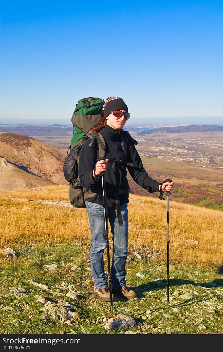 Hiker girl in sunglasses and with hiking poles on the mountain summit. Hiker girl in sunglasses and with hiking poles on the mountain summit