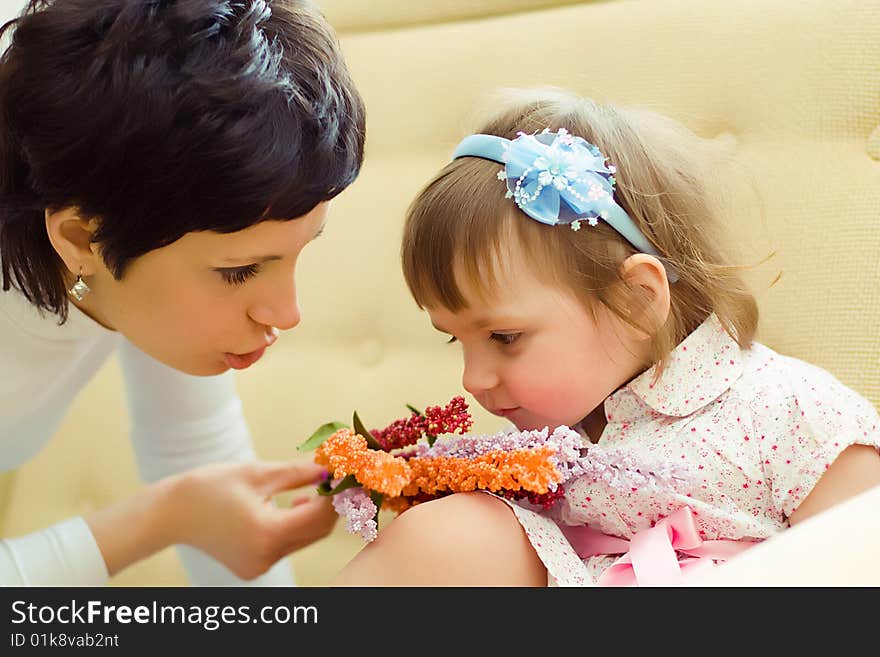 Girl with mother sniffing flowers