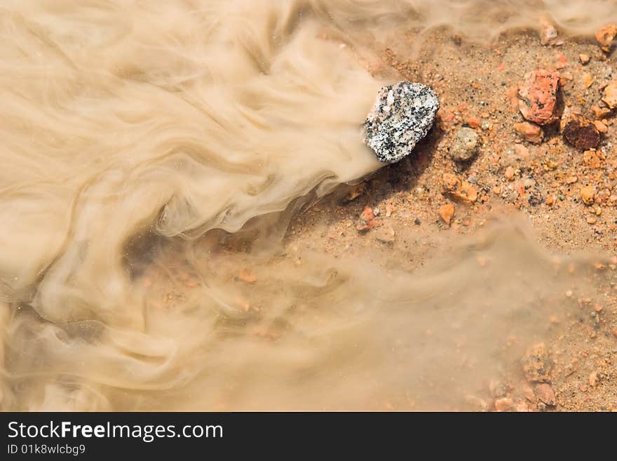 Stream of the dissolved clay, coffee with milk colour. Stream of the dissolved clay, coffee with milk colour