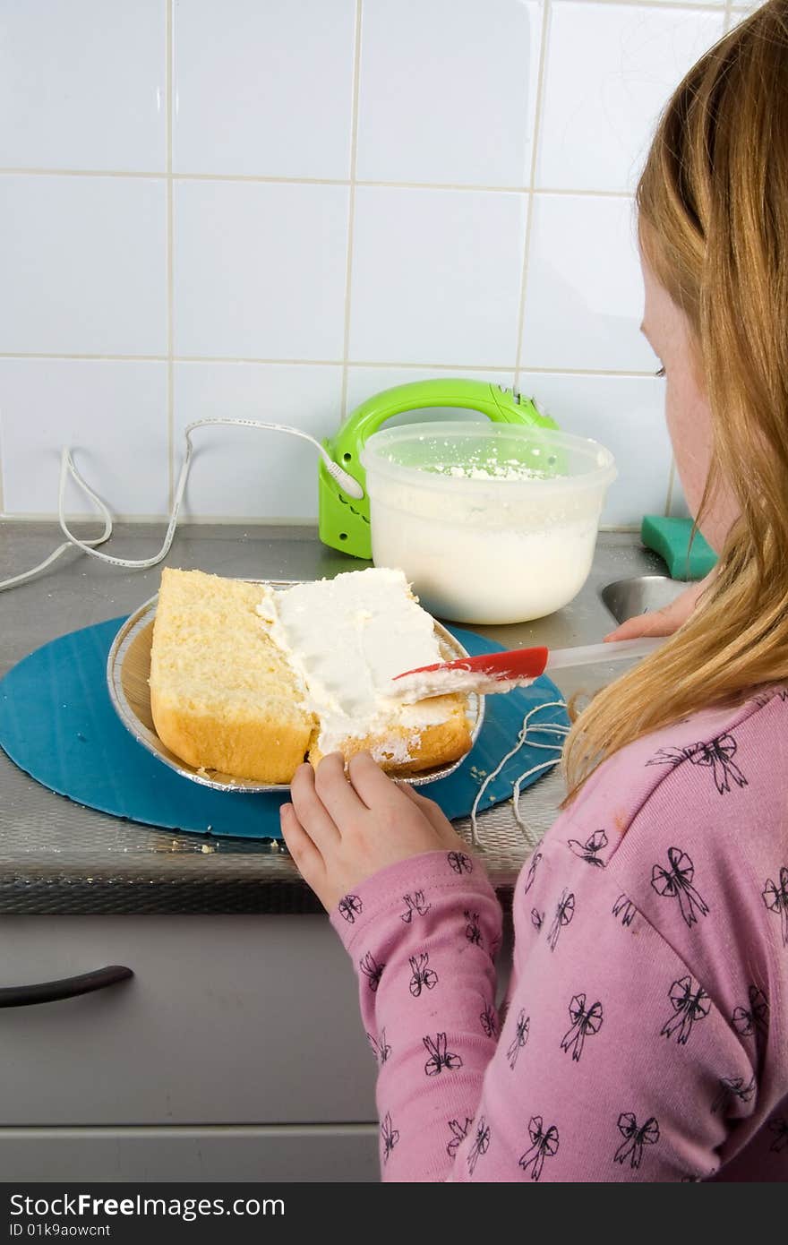 Girl is decorating a cake with whipped cream