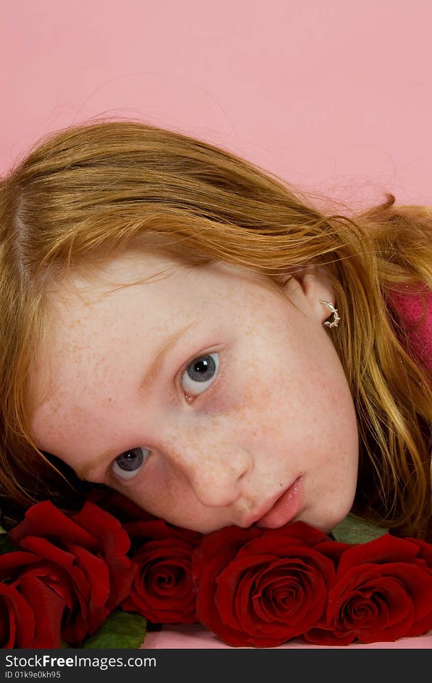 Red head girl laying on some red roses