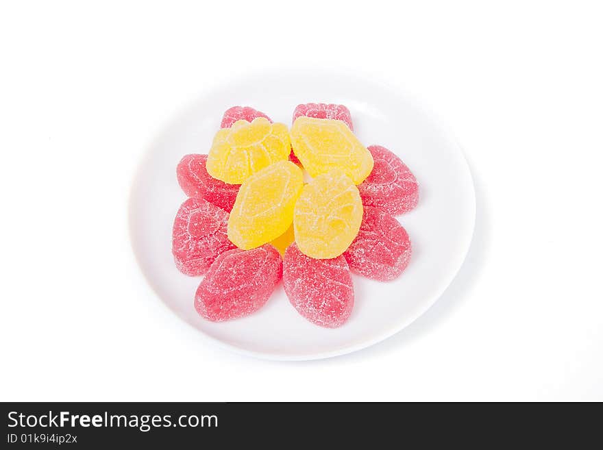 Red and yellow gumdrops on white saucer, isolated on white. Red and yellow gumdrops on white saucer, isolated on white