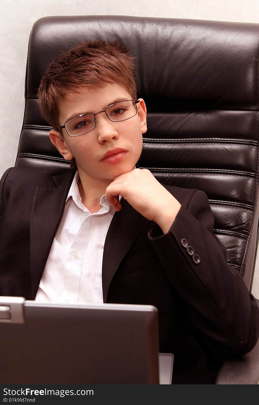 A boy sitting in large  chair  with a notebook. A boy sitting in large  chair  with a notebook