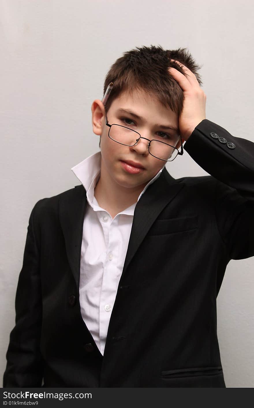 The boy keeping for a head a hand in points and a business suit on a white background. The boy keeping for a head a hand in points and a business suit on a white background