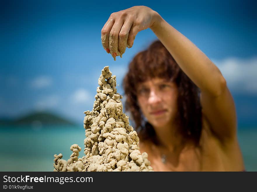 A woman building a sandcastle on the beach.