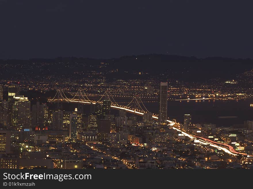 San Francisco skyline at dusk with view of Baybridge and dark sky. San Francisco skyline at dusk with view of Baybridge and dark sky.