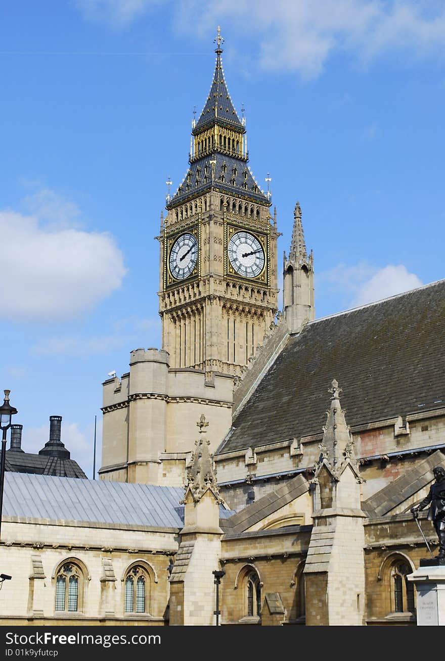 Big Ben peeks out from behind the buildings of London set against a blue sky. Big Ben peeks out from behind the buildings of London set against a blue sky.