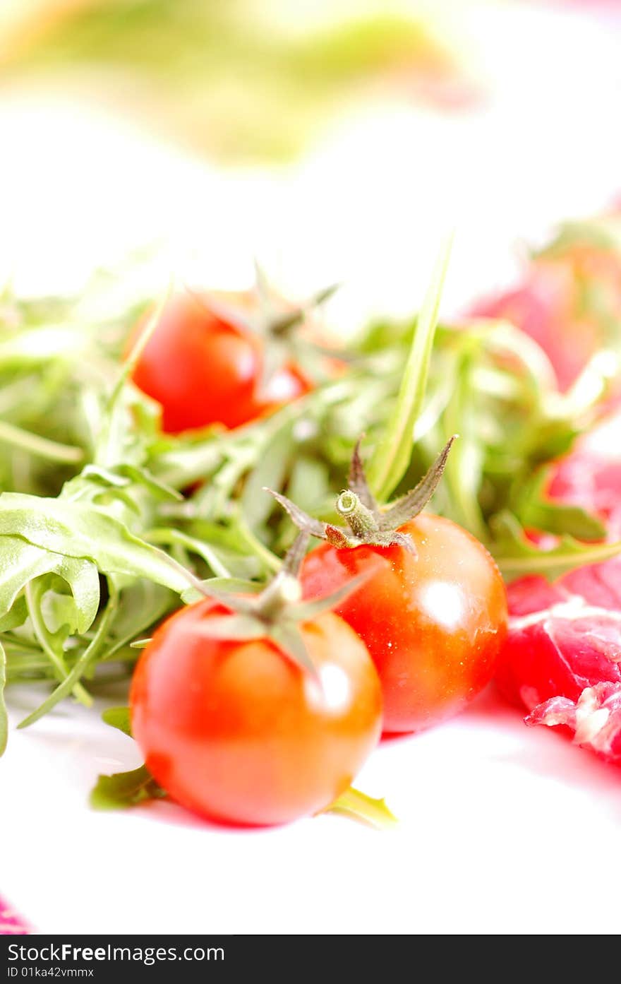 Raw meet with tomatoes and rocket salad