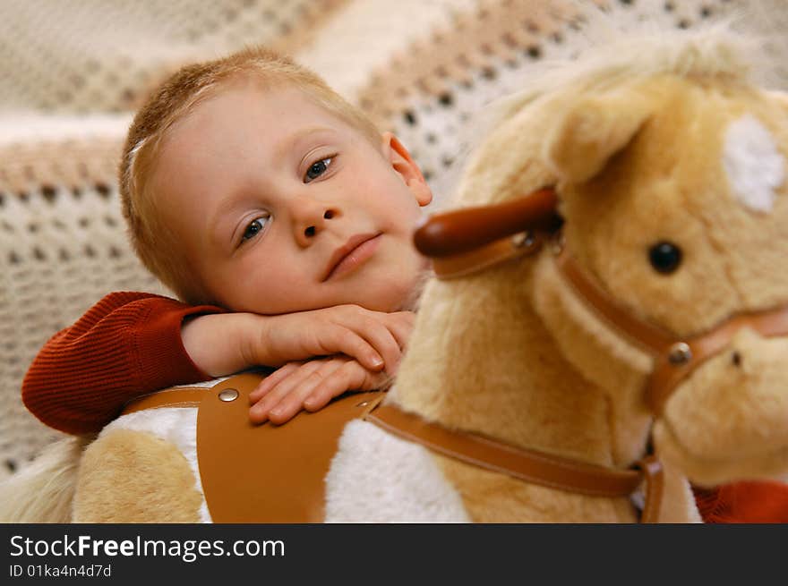 A young boy pauses from riding his toy horse to rest for a moment and have his photo taken. A young boy pauses from riding his toy horse to rest for a moment and have his photo taken.