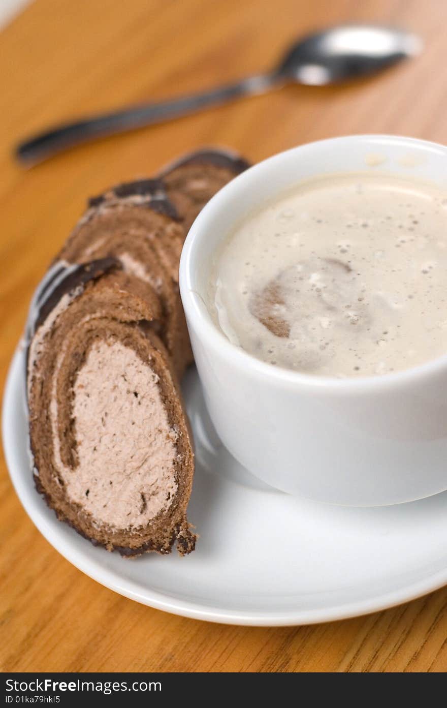 Close-up cup of coffee with dessert and spoon on the wooden table