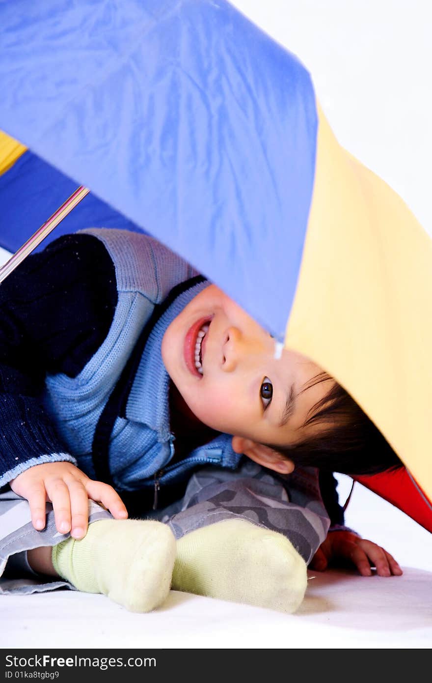 A picture of a little chinese boy looking outward under a colorful umbrella. A picture of a little chinese boy looking outward under a colorful umbrella