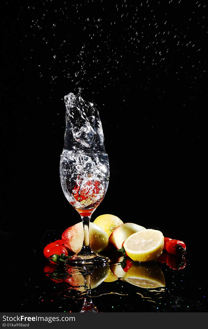 Blank background, red tomatos falling into water in a goblet, peach, tomatoes, lemon on the desk, with their reflection. Blank background, red tomatos falling into water in a goblet, peach, tomatoes, lemon on the desk, with their reflection