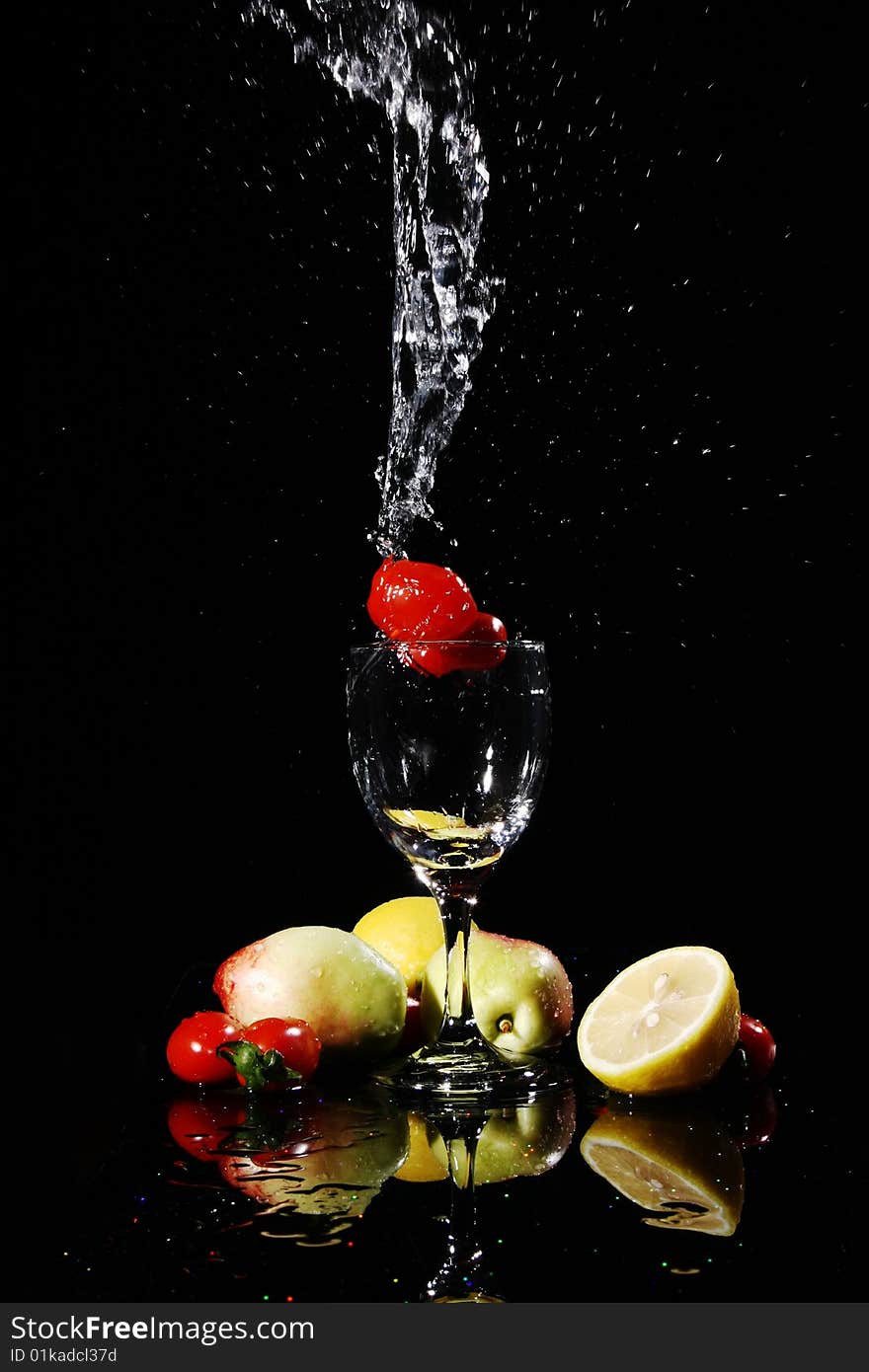 Blank background, red tomatos falling into water in a goblet, peach, tomatoes, lemon on the desk, with their reflection. Blank background, red tomatos falling into water in a goblet, peach, tomatoes, lemon on the desk, with their reflection