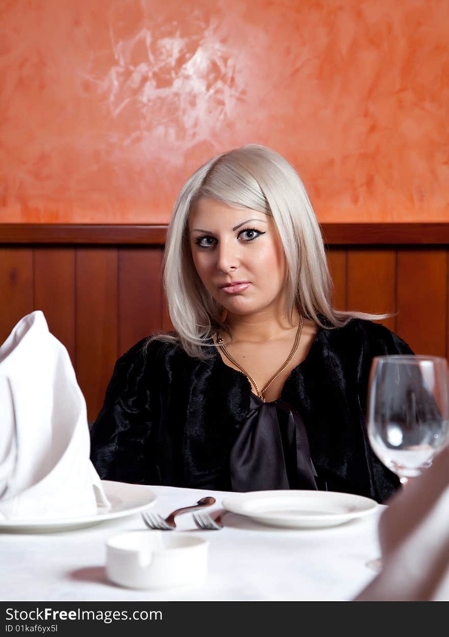 Charming blond girl sitting at a table in a restaurant