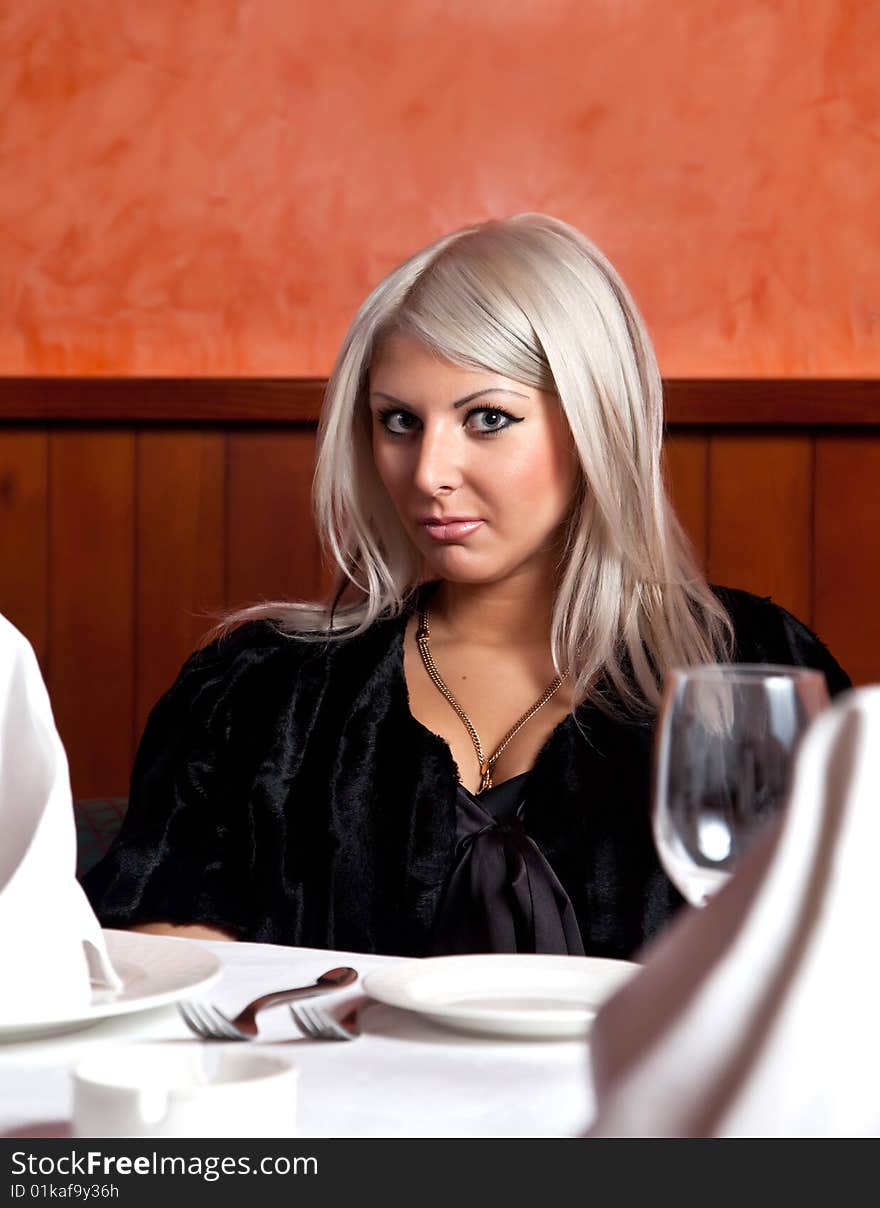 Charming blond girl sitting at a table in a restaurant