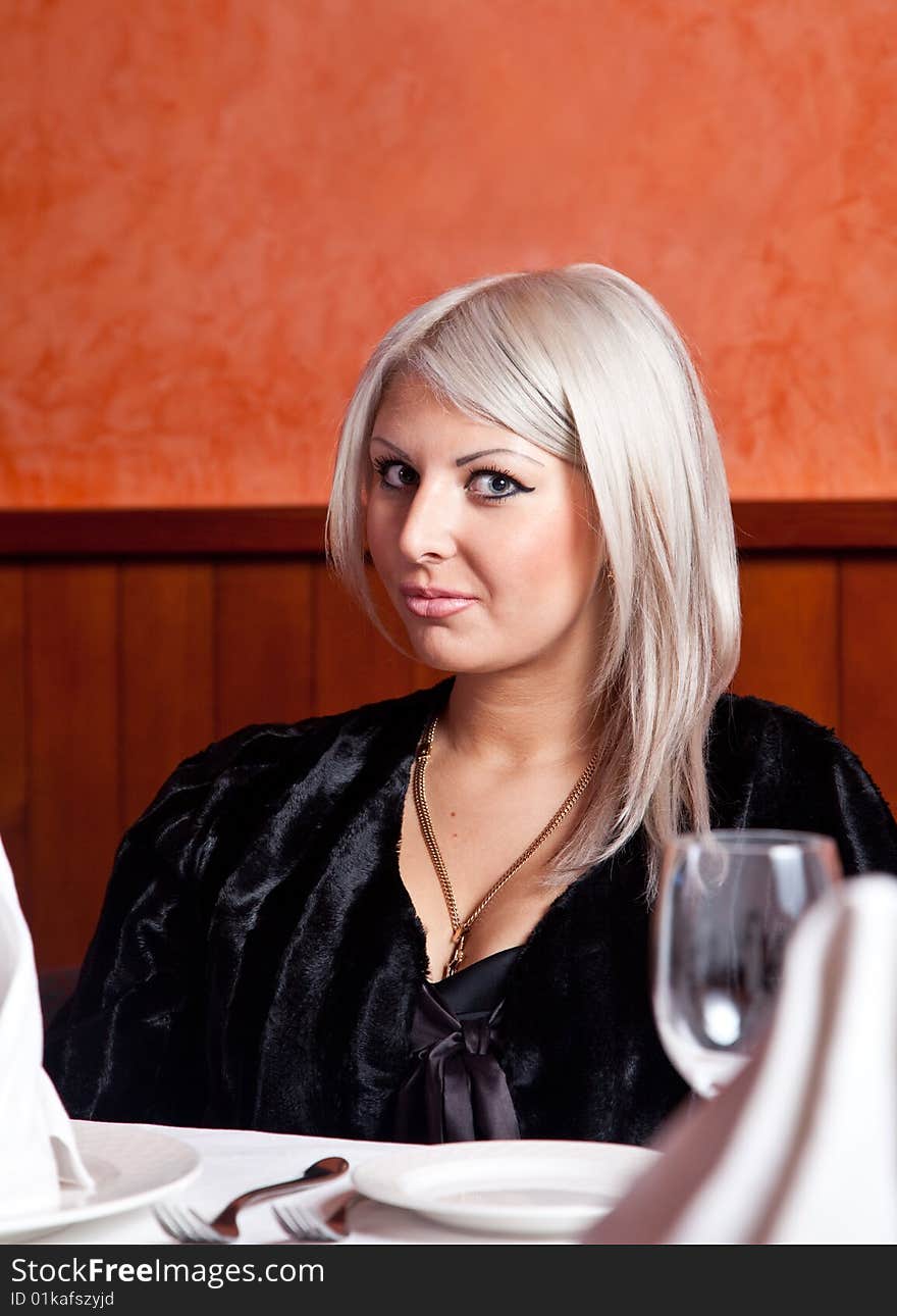 Charming blond girl sitting at a table in a restaurant