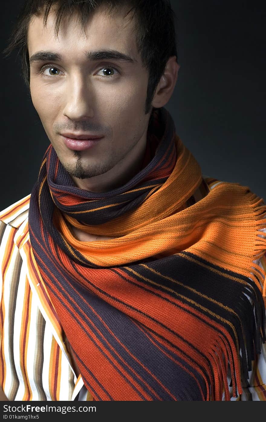 Portrait of a young handsome man with colorful scarf on dark background. Portrait of a young handsome man with colorful scarf on dark background