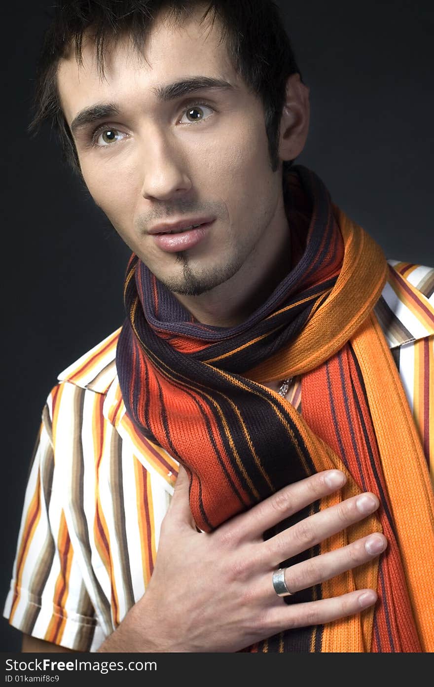 Portrait of a young handsome man with colorful scarf on dark background. Portrait of a young handsome man with colorful scarf on dark background