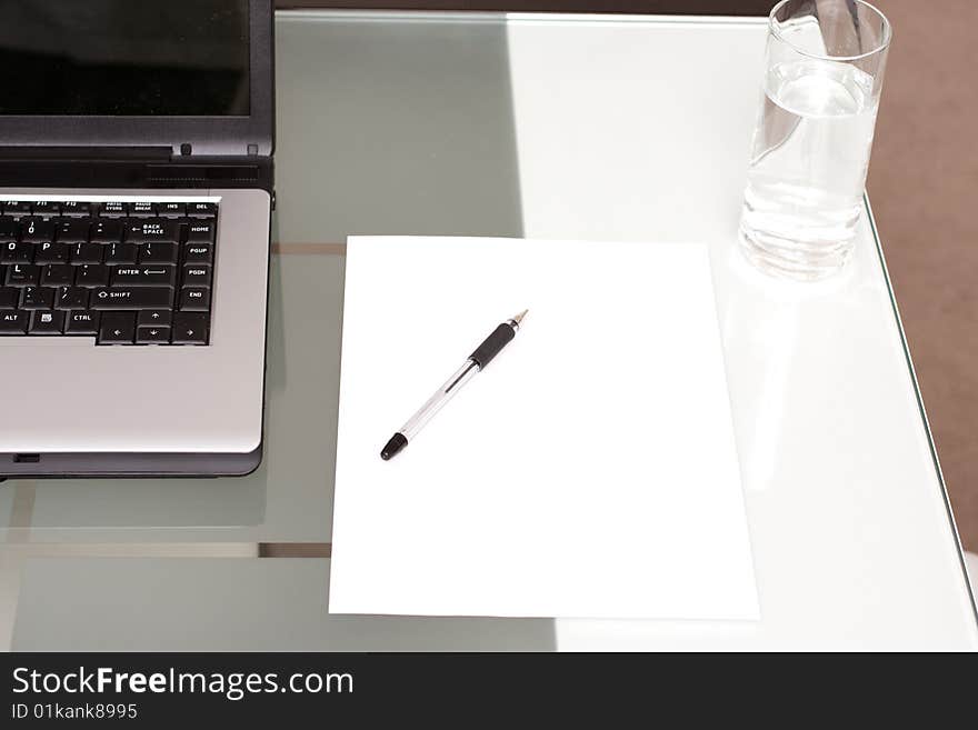 Laptop, blank paper and glass of water to display a working from home environment. Laptop, blank paper and glass of water to display a working from home environment.