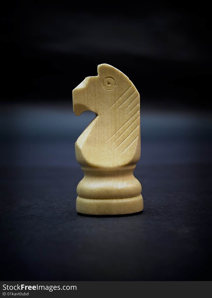 Knight, wooden chess piece isolated on dark background.