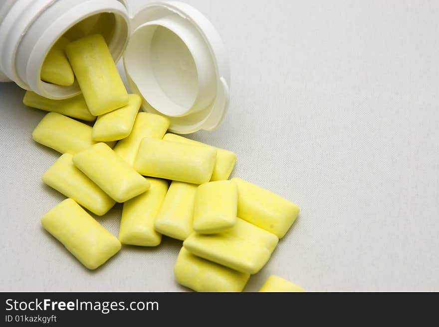 Yellow pills out of container with light background