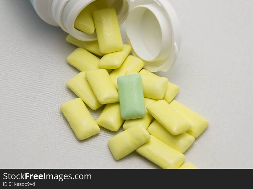 Yellow pills out of container with light background and a different pill