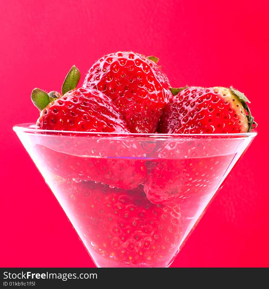 Strawberries in glass on pink background