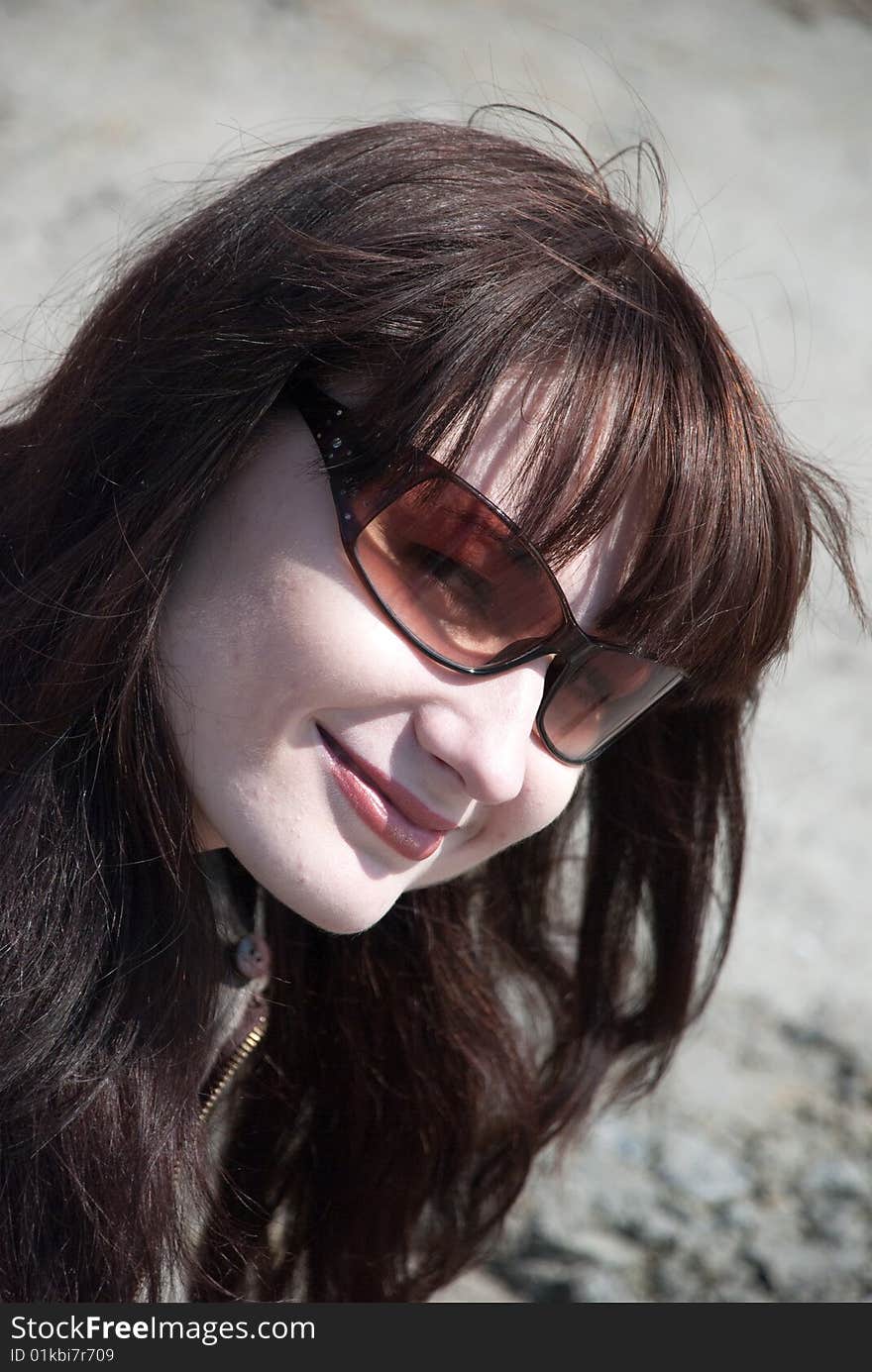 A girl with sun glasses smile on a stone background