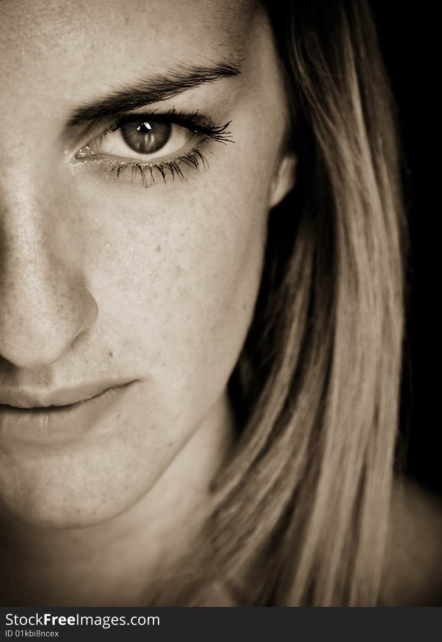 Young blonde against black background, sepia tone. Young blonde against black background, sepia tone.