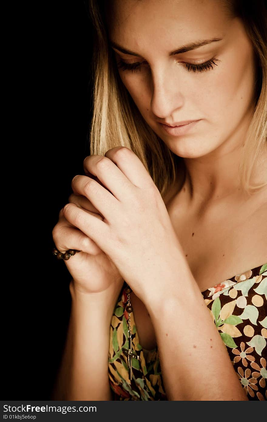 Blond praying woman against black background