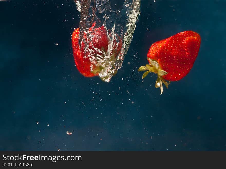 Fresh strawberries dropped into water